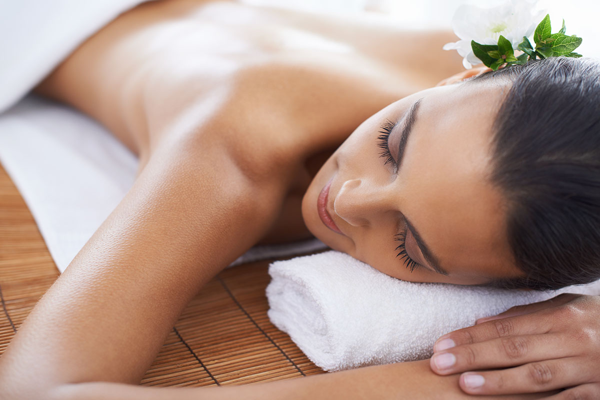 Relaxed woman lying on a massage table with a flower in her hair.